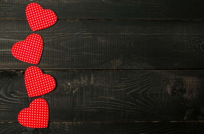 Red polka dot fabric hearts arranged in a checkmark on dark wood background - perfect for Valentine's Day promotions or romantic home decor inspiration. Shop now at D1gital Emporium US.
