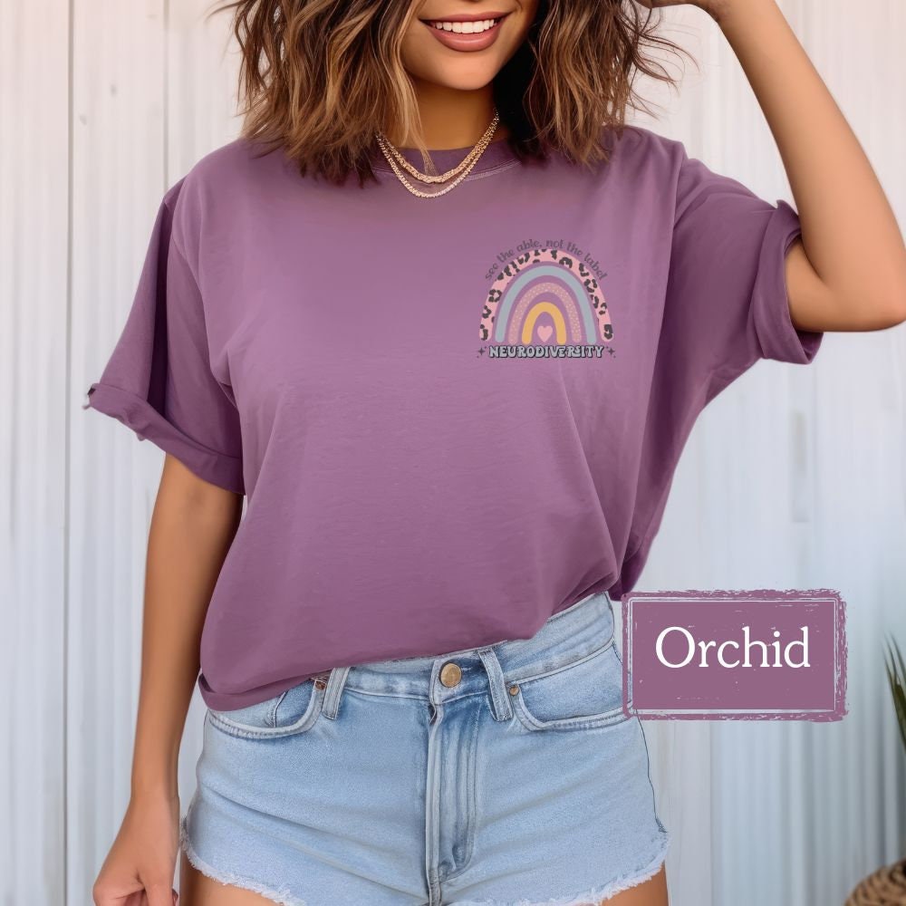 Woman wearing an orchid shirt with &quot;See the Able, Not the Label&quot; and a rainbow design for autism awareness, perfect for Special Education teachers, Sped teacher gifts, and promoting neurodiversity. Great for back to school tees and autism acceptance.