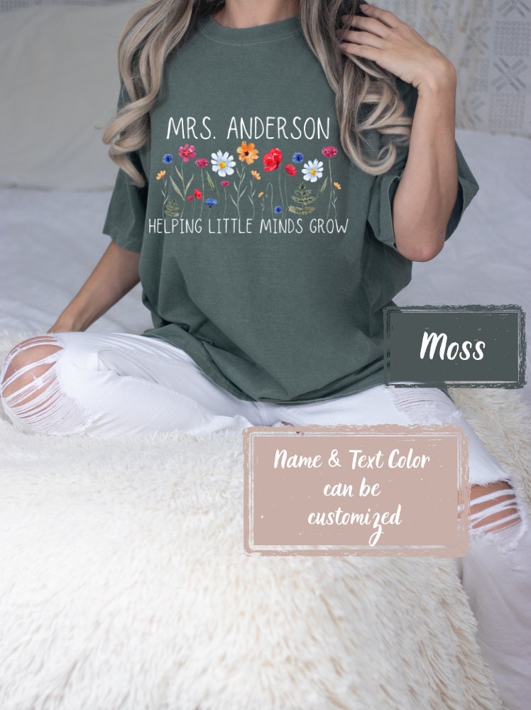 Comfort Colors Moss shirt for teachers, customizable with name. Floral design with &#39;Helping Little Minds Grow&#39; text, perfect for teacher appreciation, summer, and starting the school year