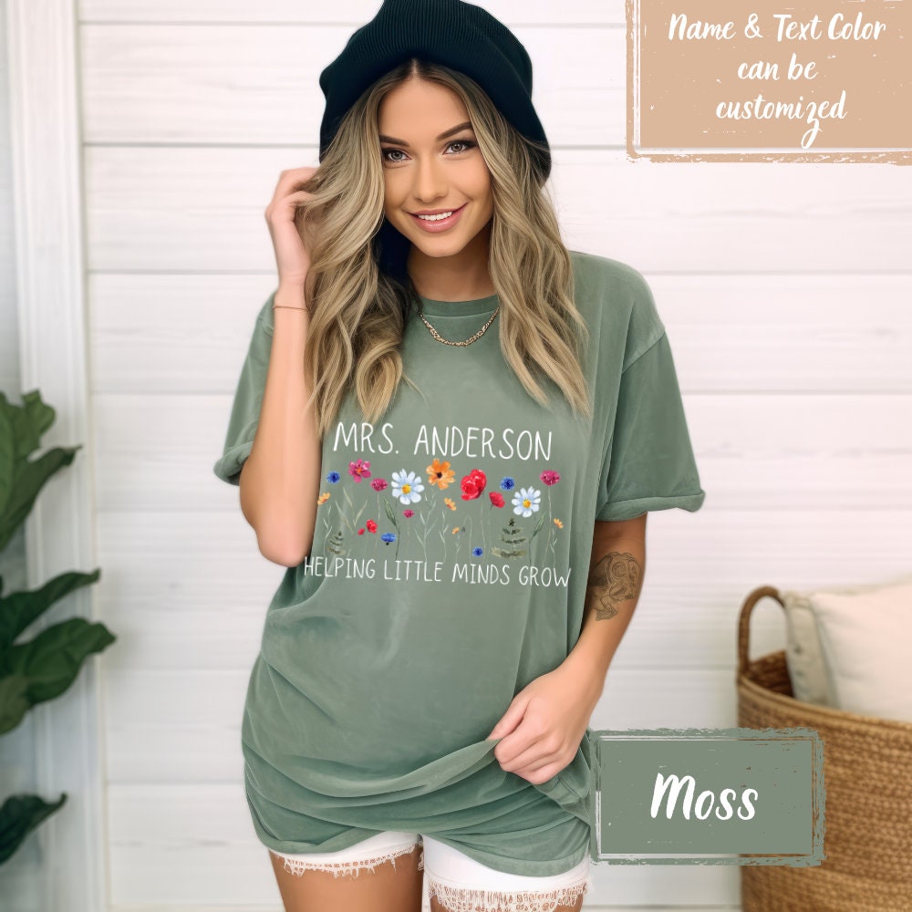 Customizable teacher summer shirt in Moss, featuring &#39;Helping Little Minds Grow&#39; with a vibrant wildflower print. Perfect appreciation gift for teachers, promoting a fun first day of school or end of year.