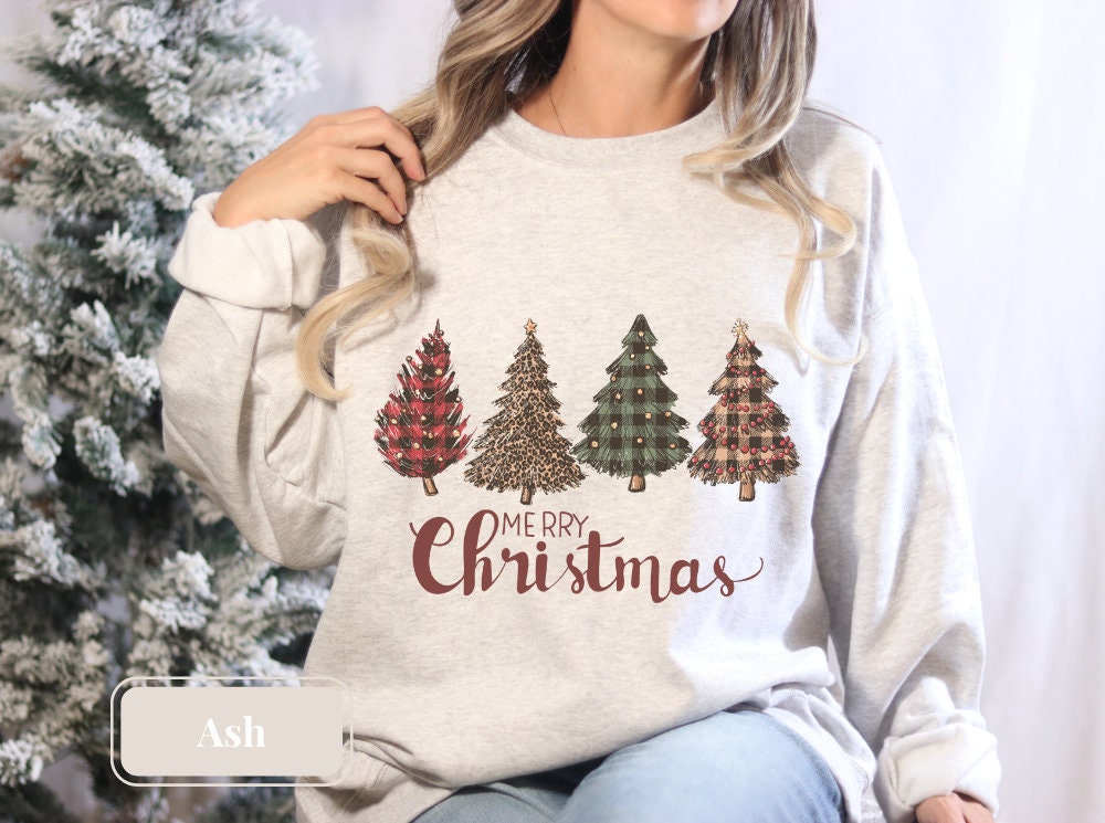 Ash crewneck sweatshirt featuring festive Christmas trees and &#39;Merry Christmas&#39; text. Great tree sweatshirt, holiday sweatshirt, and winter shirt. Perfect Christmas gift and Christmas crewneck for holiday celebrations and winter fun.