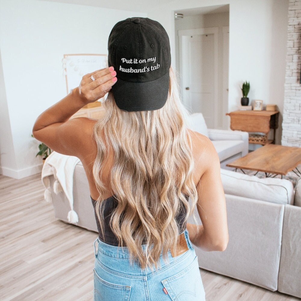 A classic black dad hat featuring &quot;Put it on my husband&#39;s tab&quot; embroidery. Perfect gift for dad, wife, or bride. Funny, sarcastic, and stylish. Ideal for vintage fashion lovers and versatile wear.