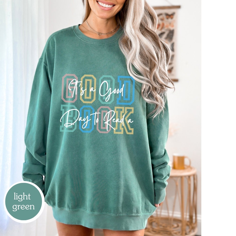 Comfort Colors sweatshirt in light green with &#39;It’s a Good Day to Read a Book&#39; design. Ideal for book lovers, teachers, and book clubs. Perfect for trendy literary shirts and teacher appreciation gifts.