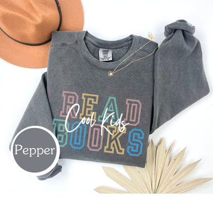 Comfort Colors sweatshirt in Pepper with &quot;cool kids read books&quot; design. Ideal for book lovers, teachers, and book clubs. Perfect for trendy literary shirts and teacher appreciation gifts.