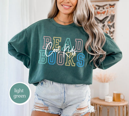 Comfort Colors sweatshirt in light green with &quot;cool kids read books&quot; design. Ideal for book lovers, teachers, and book clubs. Perfect for trendy literary shirts and teacher appreciation gifts.