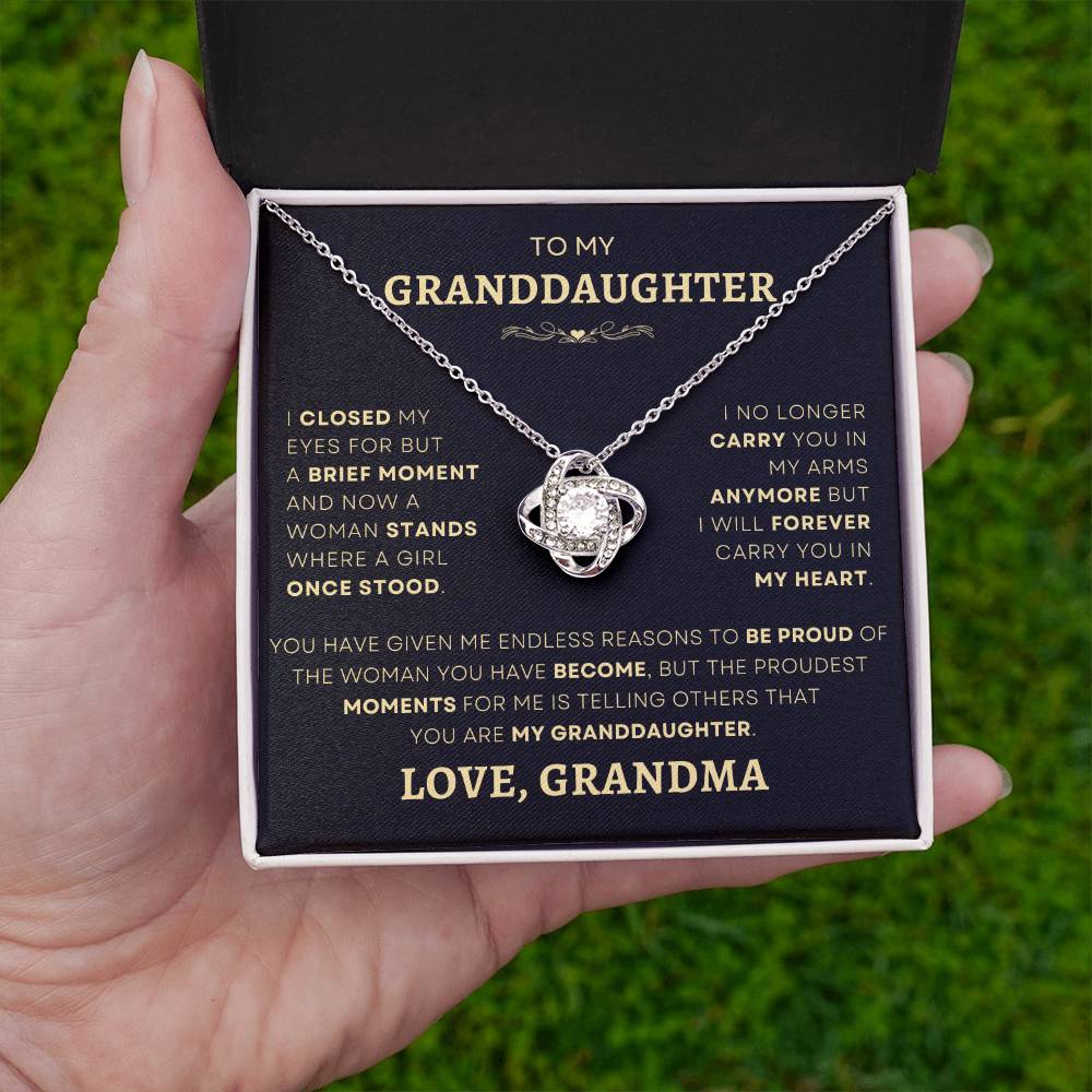 Hand holding a Loveknot Necklace with a heartfelt message from grandma to granddaughter - a thoughtful jewelry gift, find it at D1gital Emporium US.