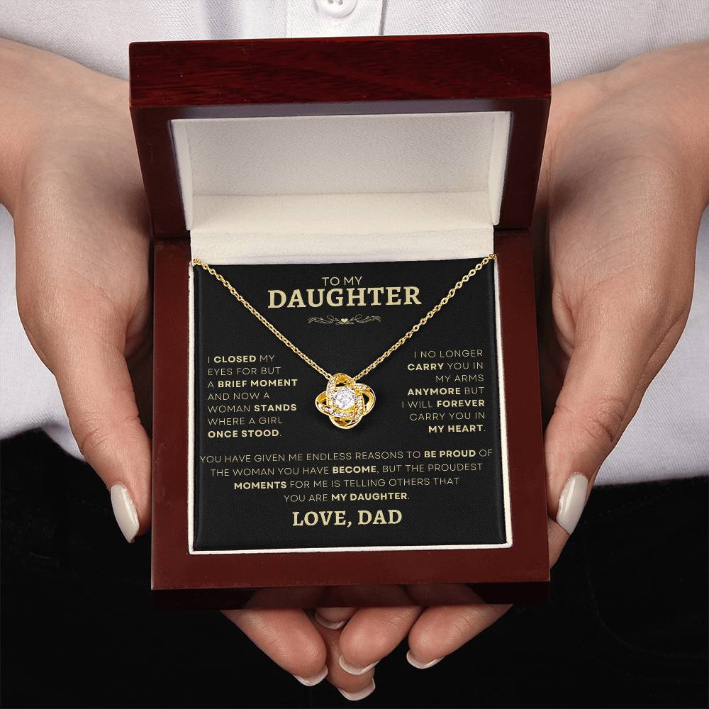 Hands presenting a Father-Daughter Gold Heart Necklace in an elegant mahogany box with a loving note, an ideal gift symbolizing a dad's eternal love.